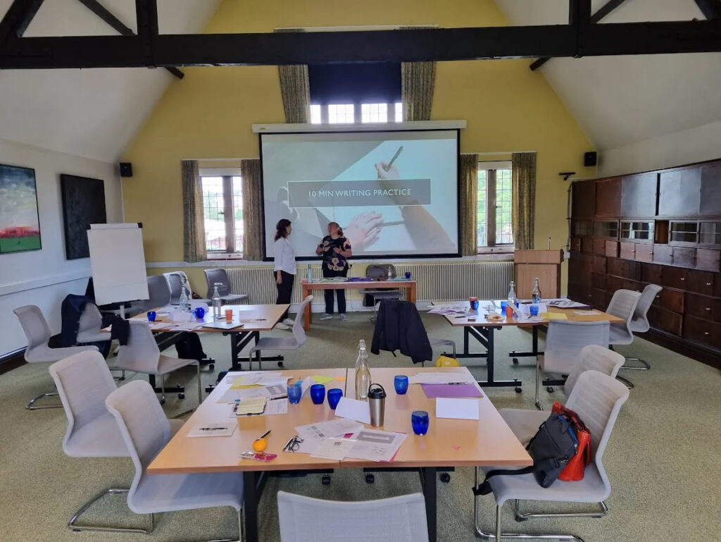 University professionals engaged in discussion during a doctoral supervision workshop, with presentation slides in the background.