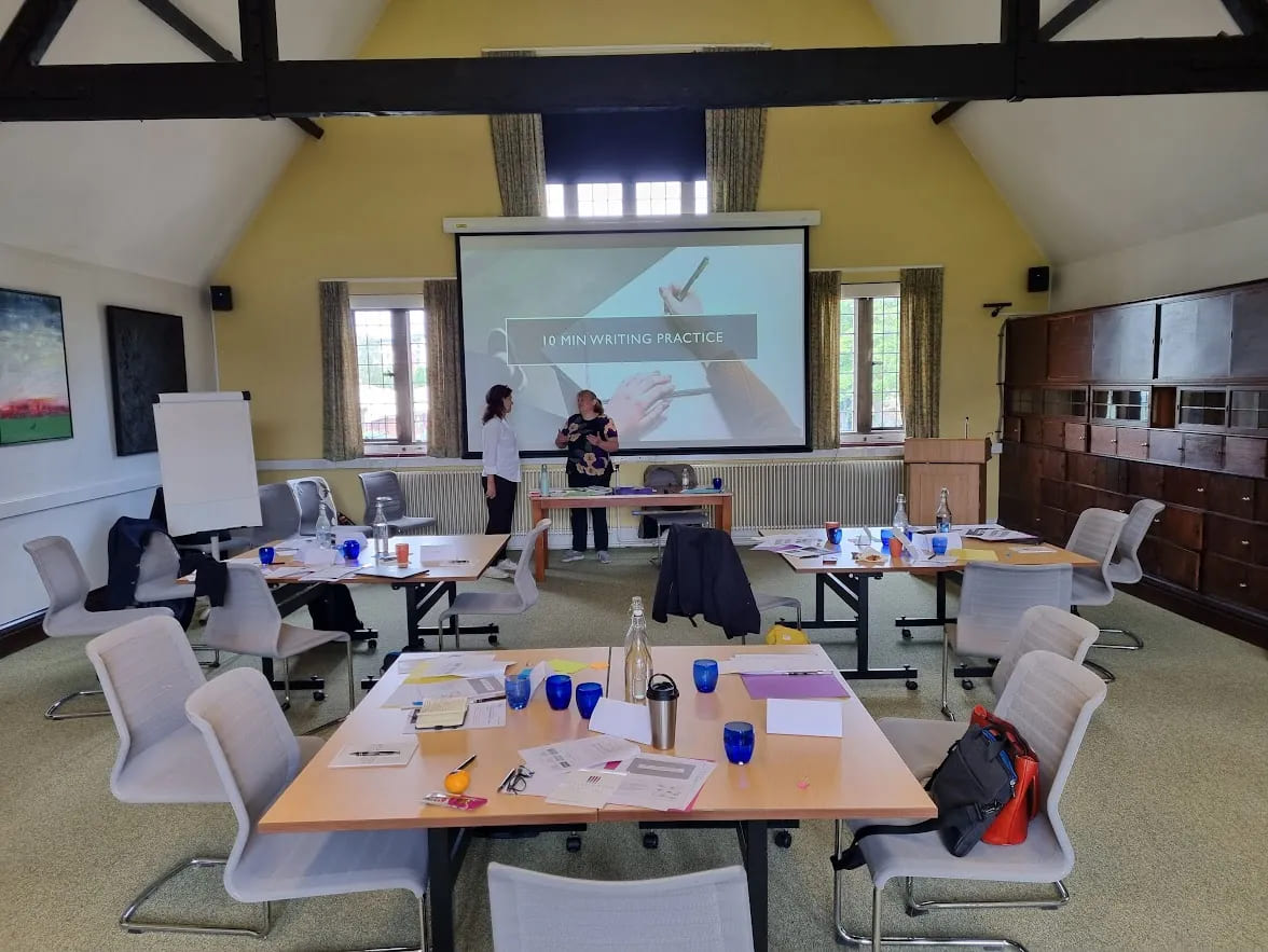 University professionals engaged in discussion during a doctoral supervision workshop, with presentation slides in the background.