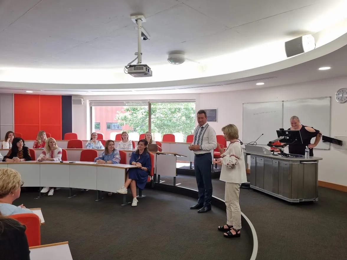 A doctoral supervision training workshop in progress, with facilitators and participants engaged in discussion in a modern seminar room.