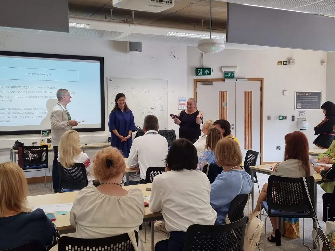 Group of doctoral supervisors attending a training session, with a facilitator presenting in front of a large screen.